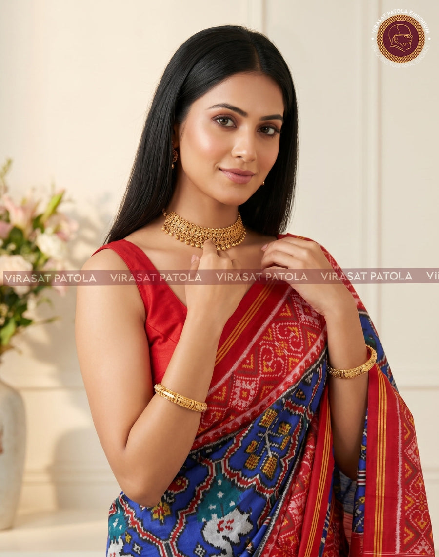 Blue patola saree pallu with red centerpiece and navy motifs; gold zari border