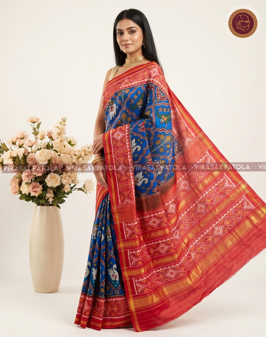 Blue patola saree with wide red pallu border and gold zari stripes, side pose