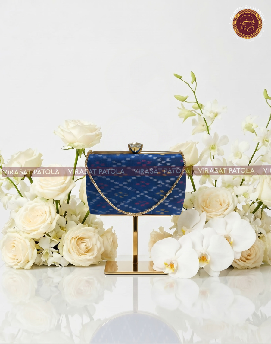 Blue patola bandhani clutch with top clasp and curved gold chain handle