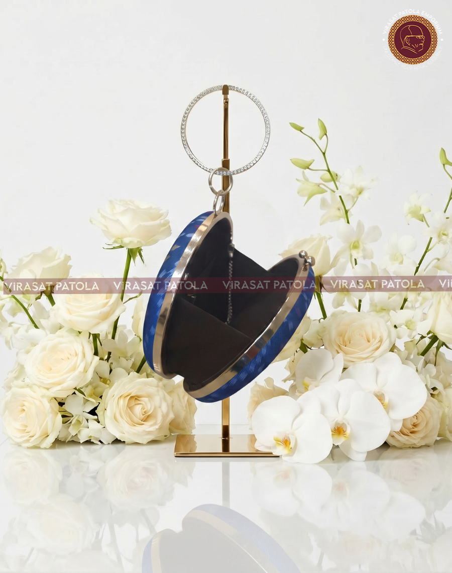 Blue round clutch with gold ring handle, dark lining, and clasp detail