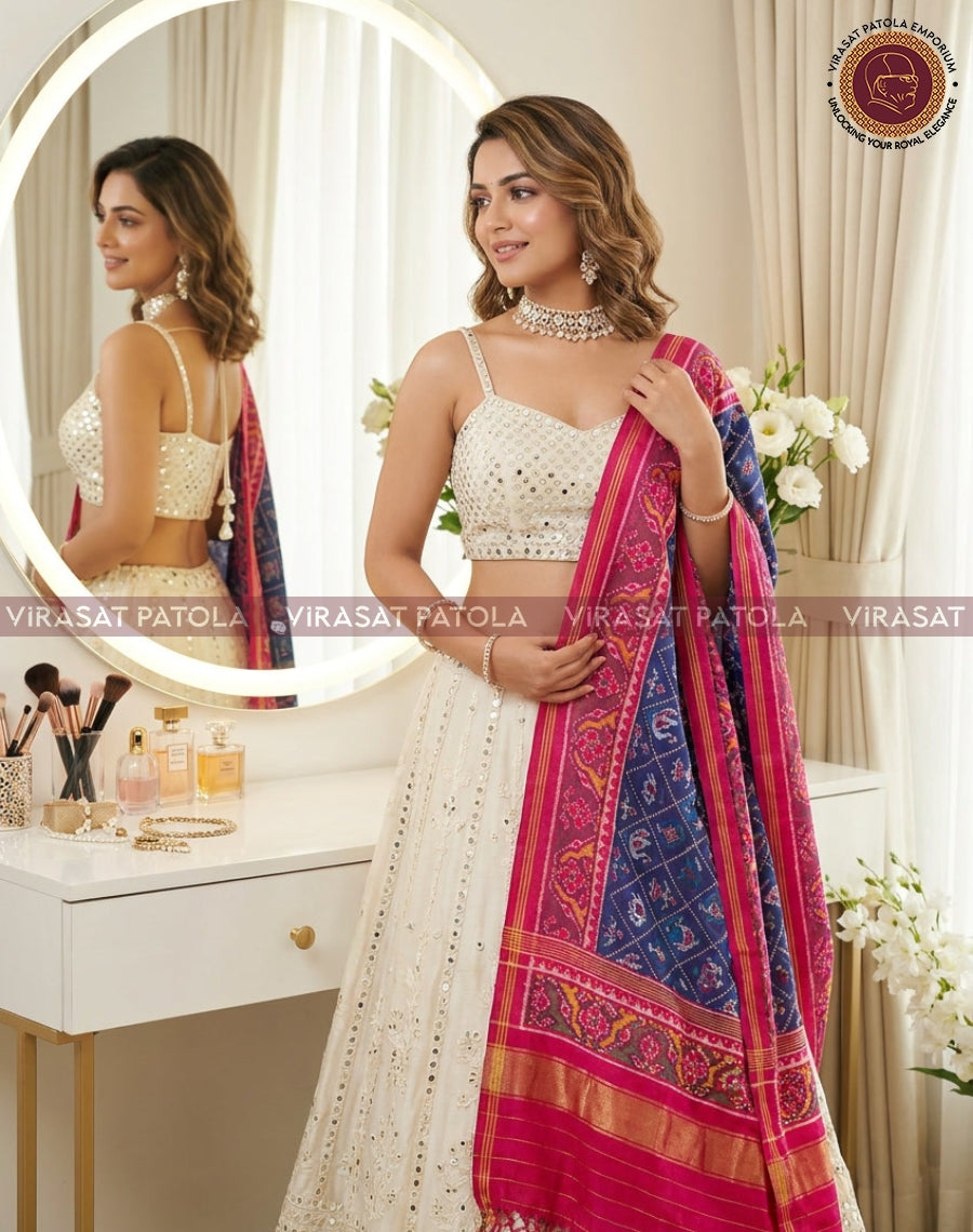 Blue patola dupatta with pink border and patterned border, held beside outfit