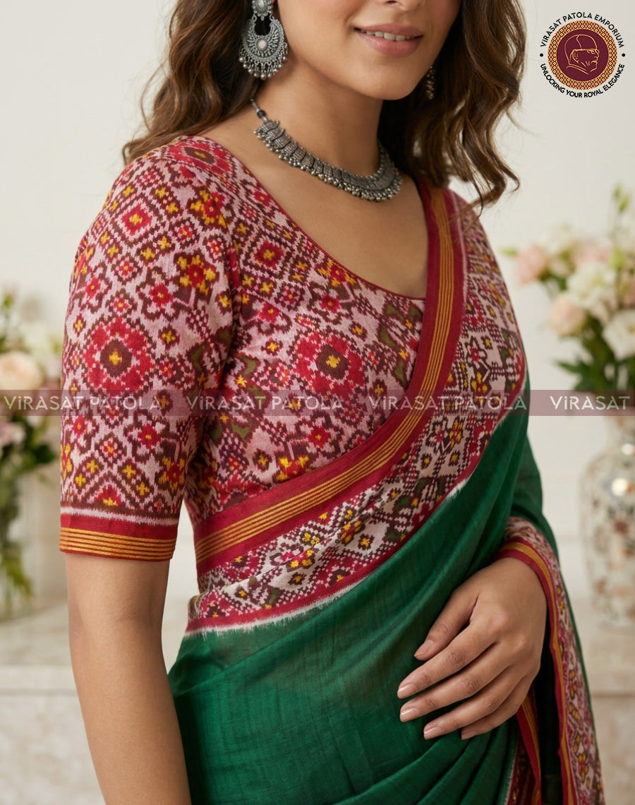 Dark green saree with red patterned blouse and gold-trimmed border, close view