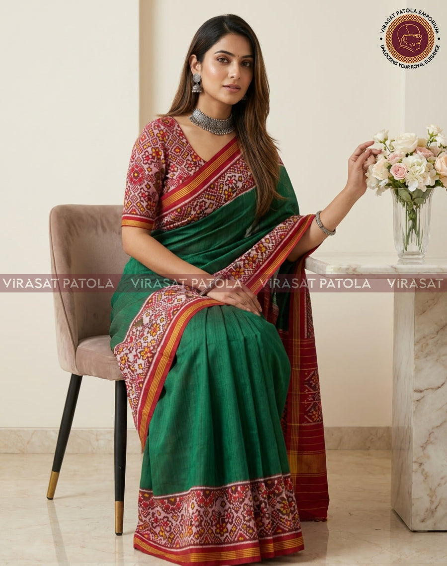 Dark green patola saree with red and gold border, worn with patterned blouse