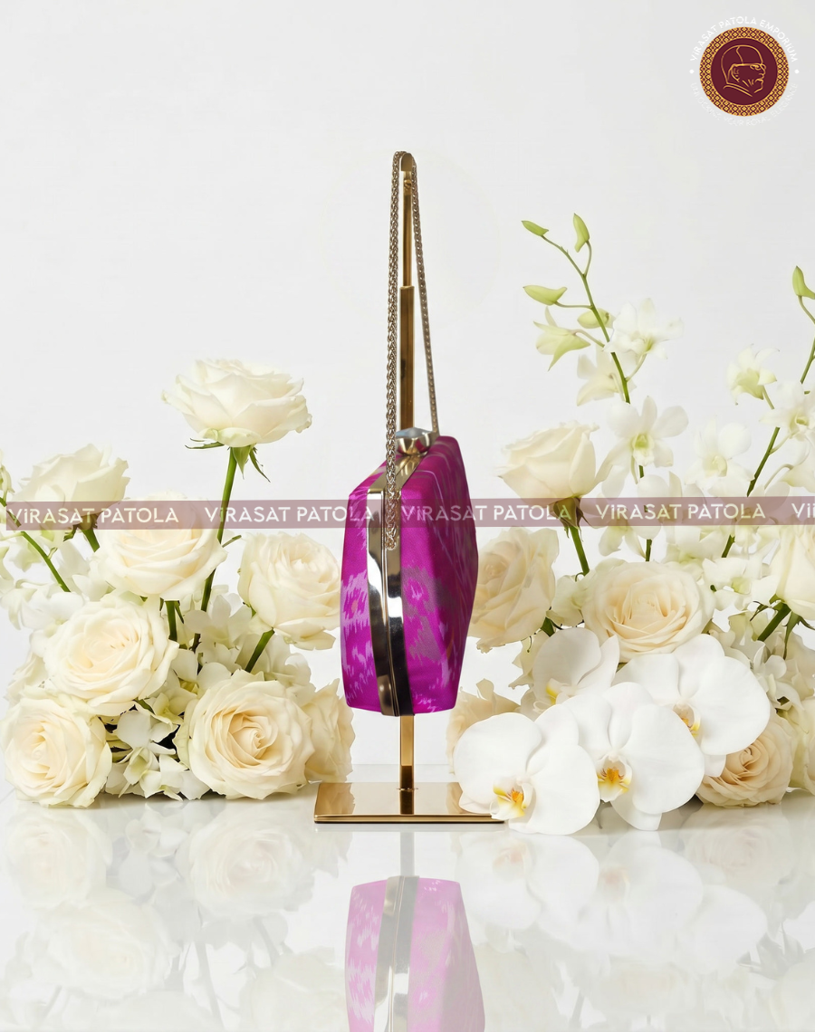 Purple ikat clutch with pink body, gold patterned handle, side angle