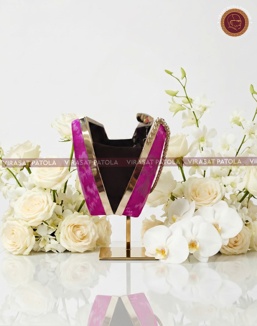 Pink patola clutch with gold-trim top and chain, black interior visible