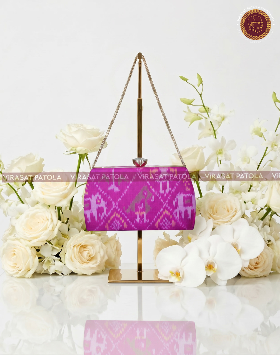 Pink patola-style clutch with purple motifs and gold chain handle, front view