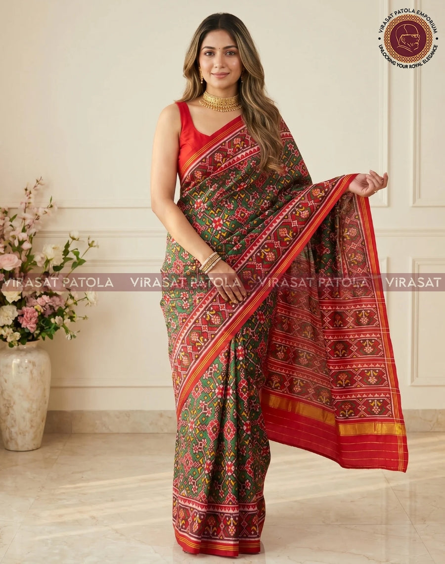 Red and green traditional saree with draped pallu, red border, and geometric motifs