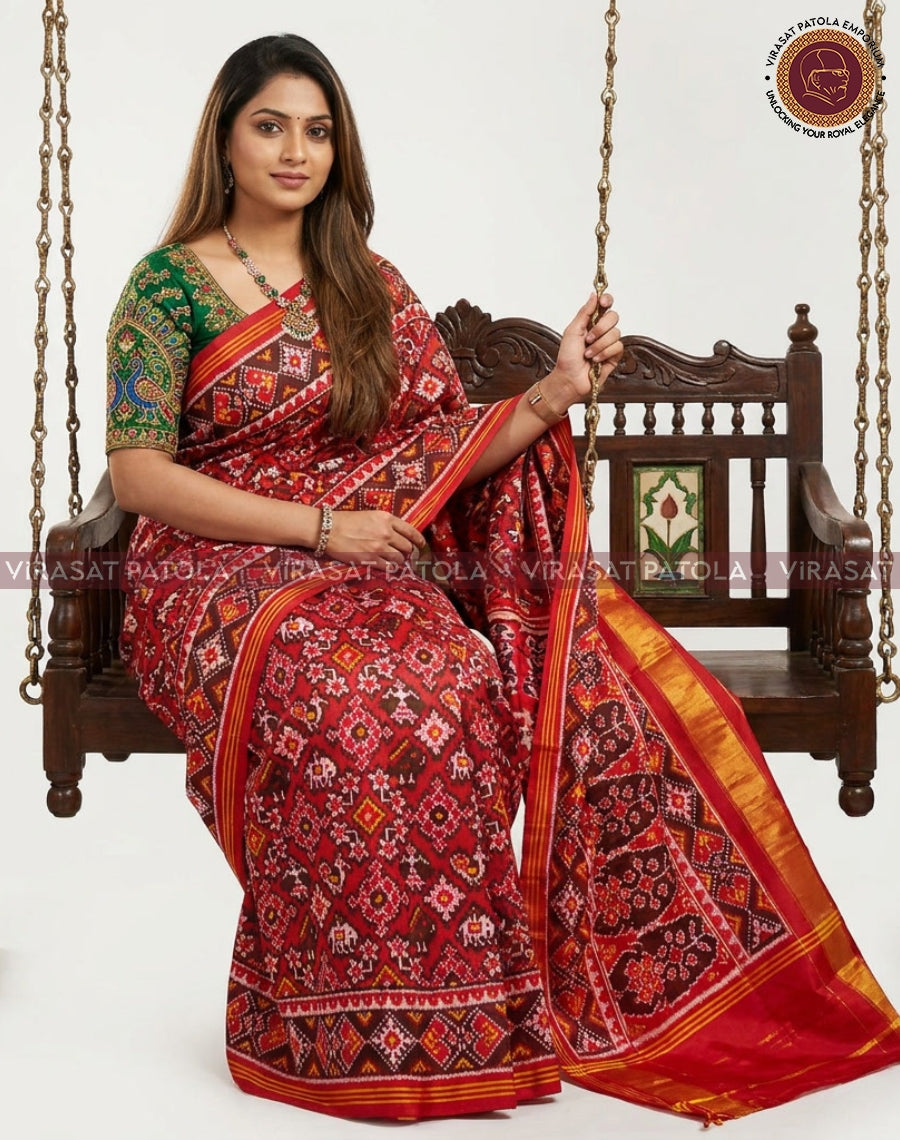 Red patola saree with ornate geometric patterns, orange-and-gold border, draped view