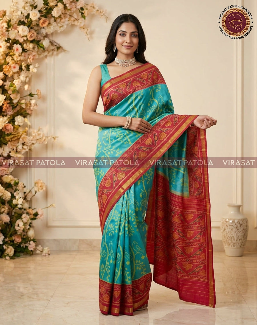 Turquoise saree with maroon-red pallu and gold motifs, draped and held at waist