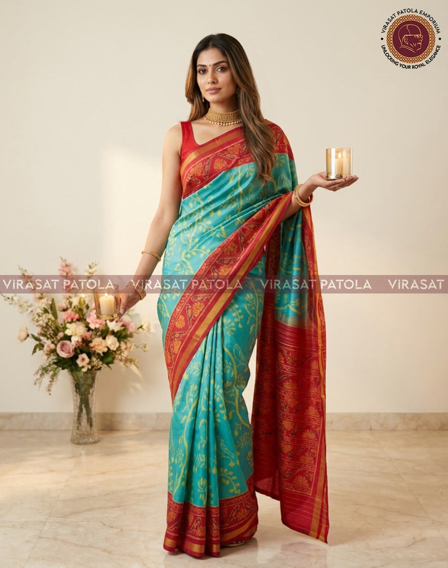 Turquoise saree with red-and-gold border pallu, draped over shoulder and side