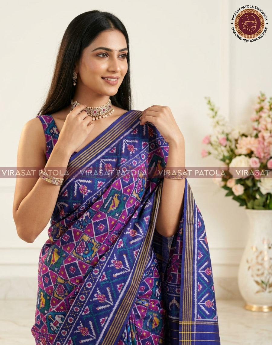 Royal blue patola saree with colorful diamond motifs, magenta highlights, and gold-striped border