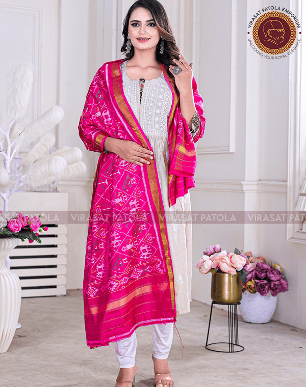 A woman wearing a traditional Indian Narikunjar dupatta in royal pink with a normal border in rich red, paired with a white and pink outfit.