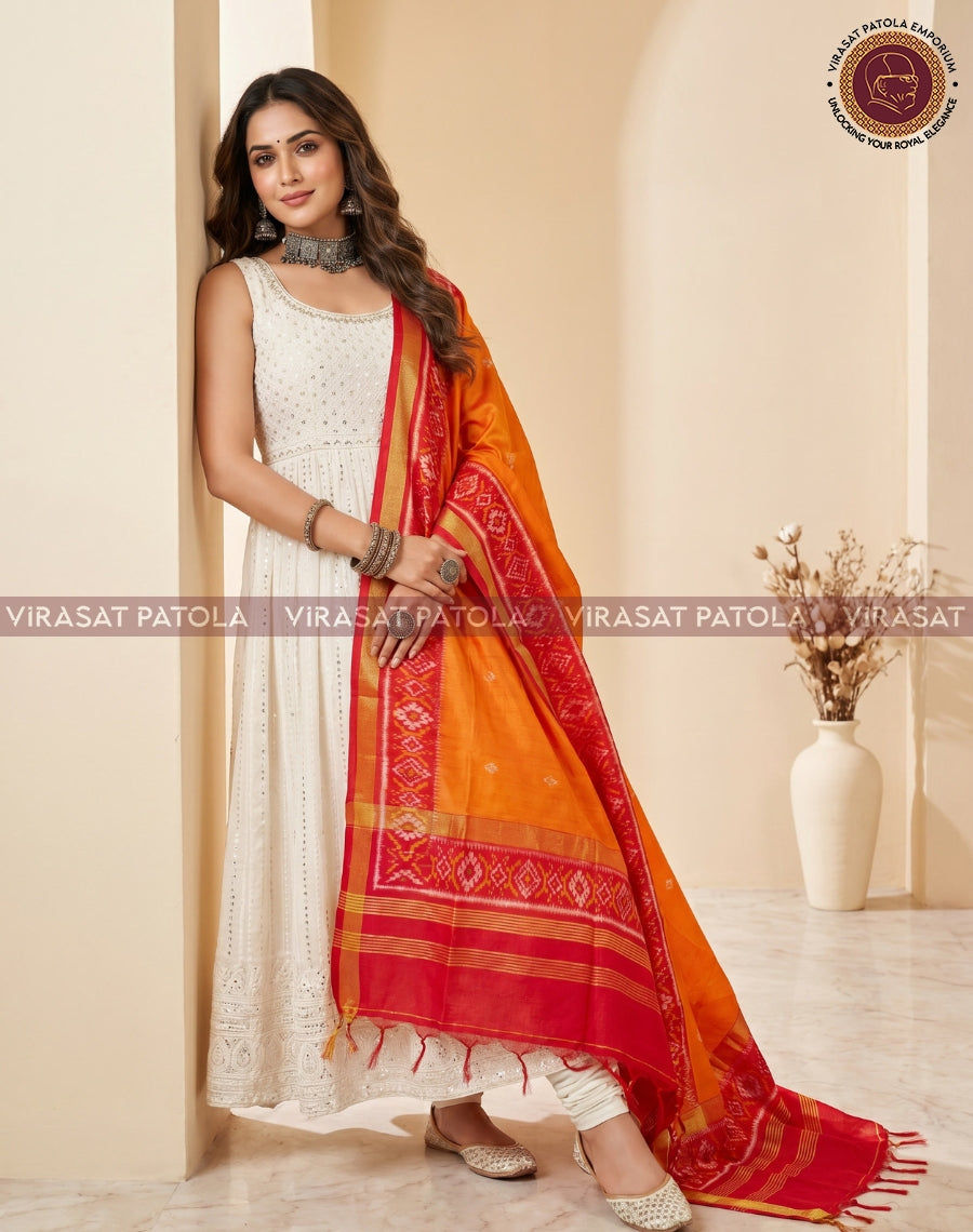 Red and orange patola dupatta with patterned bands, one end resting on the floor
